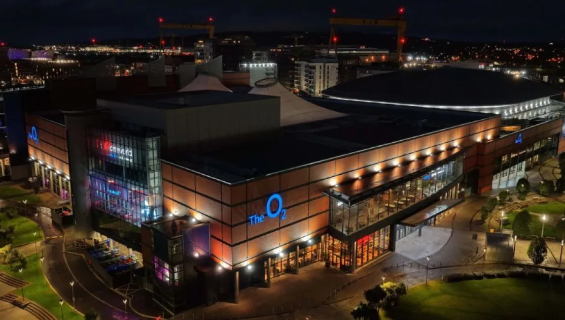 Aerial view of The O2 Belfast illuminated at night, highlighting the venue's modern exterior and surrounding cityscape.