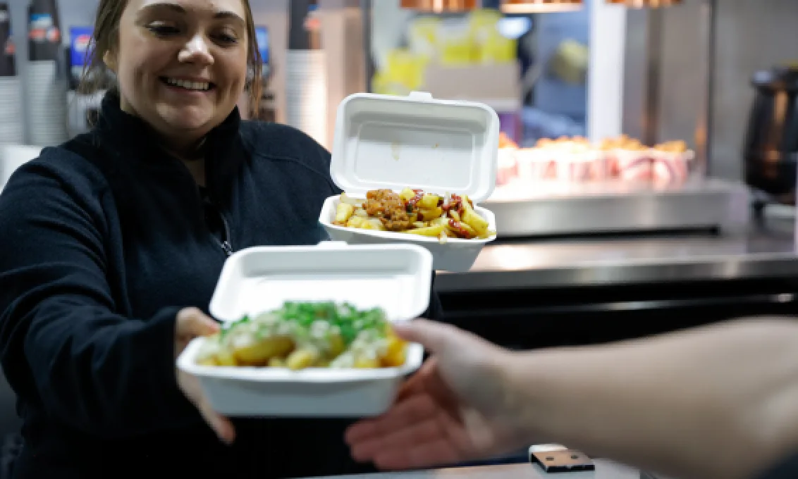 Staff member serves food from concourse unit