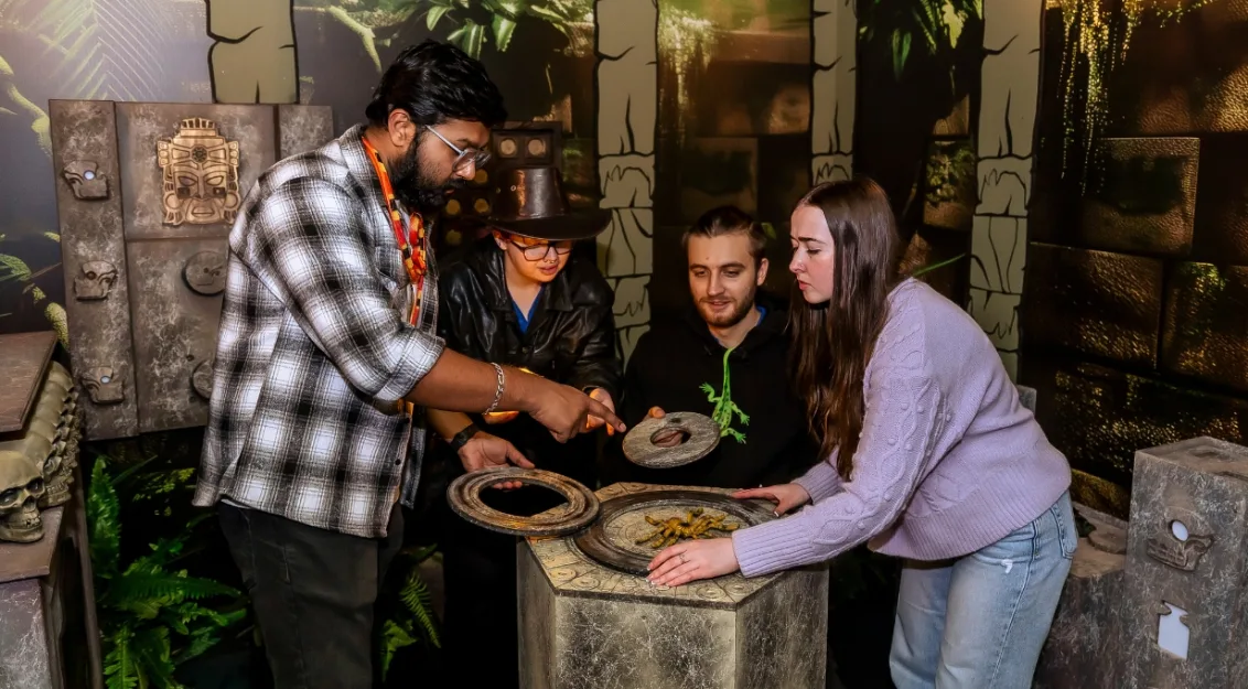 A group of people working together to solve an ancient jungle-themed escape room puzzle at Breakroom Escape Rooms