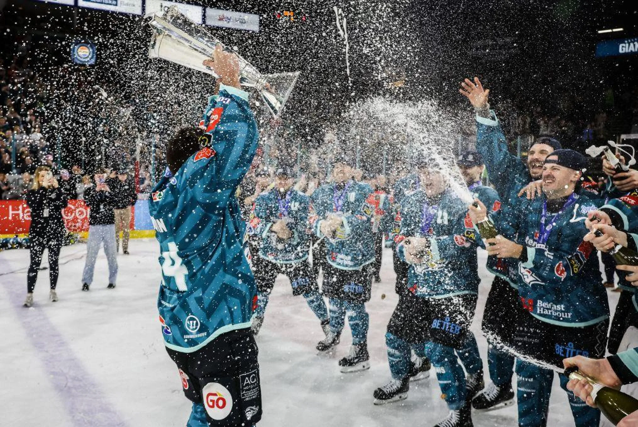 Belfast Giants players celebrate on the ice after winning the league trophy.